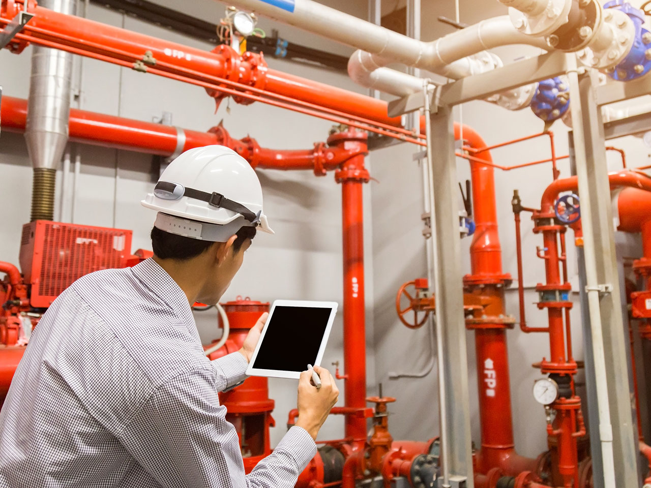 Engineer inspects red generator pump for fire sprinkler & alarm systems.