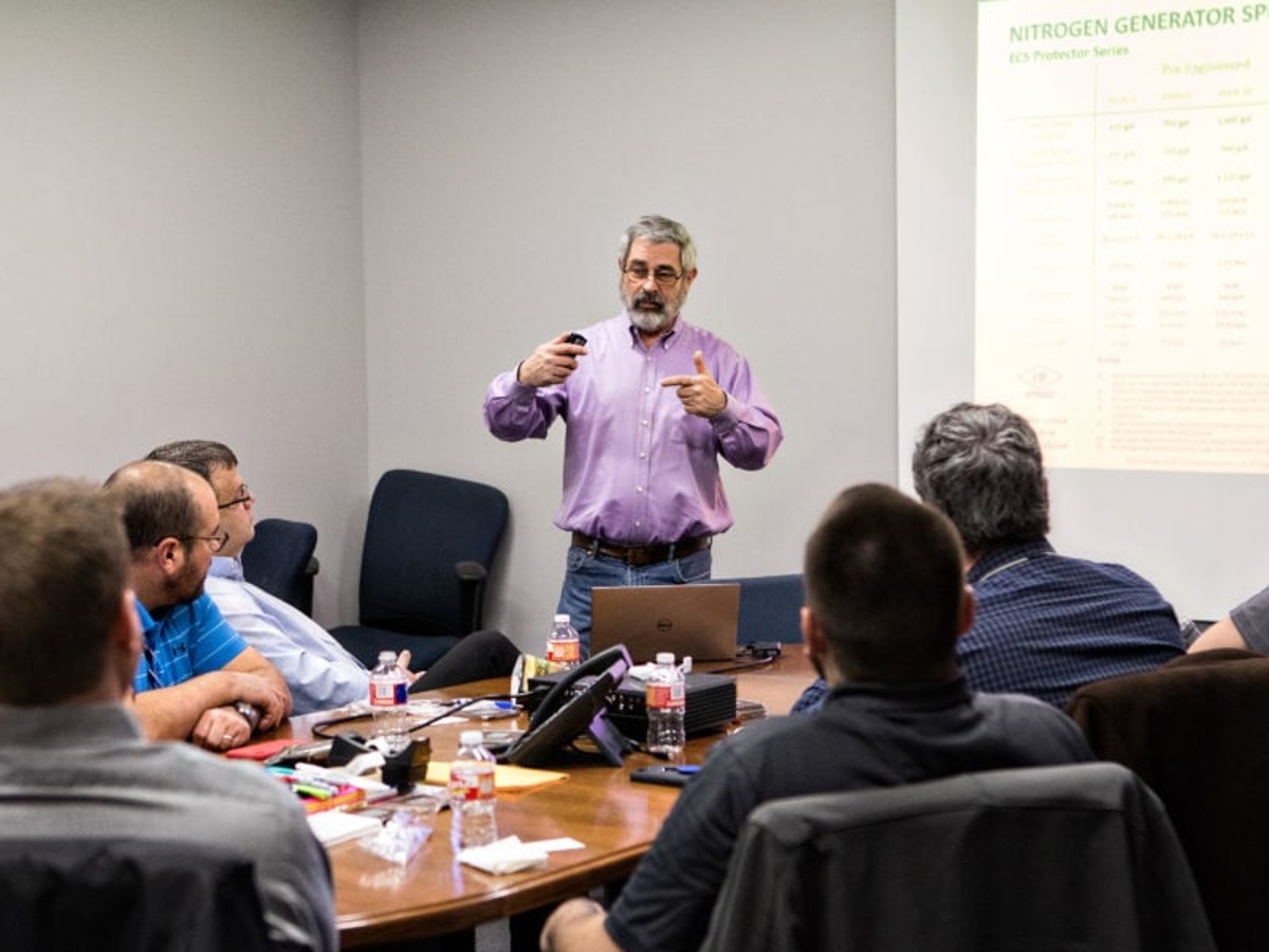 Instructor teaching a group of people at conference table.